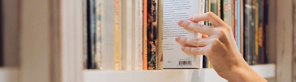 Person stellt Buch ins Regal
